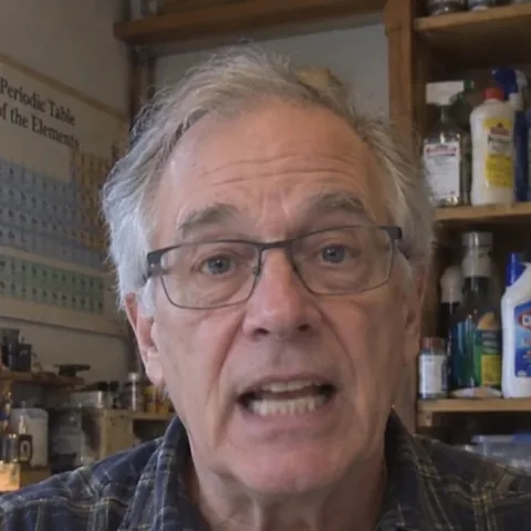 Walter Bennett, presenter of The Household Chemist, in a home workshop with cleaning products on the shelves behind him.